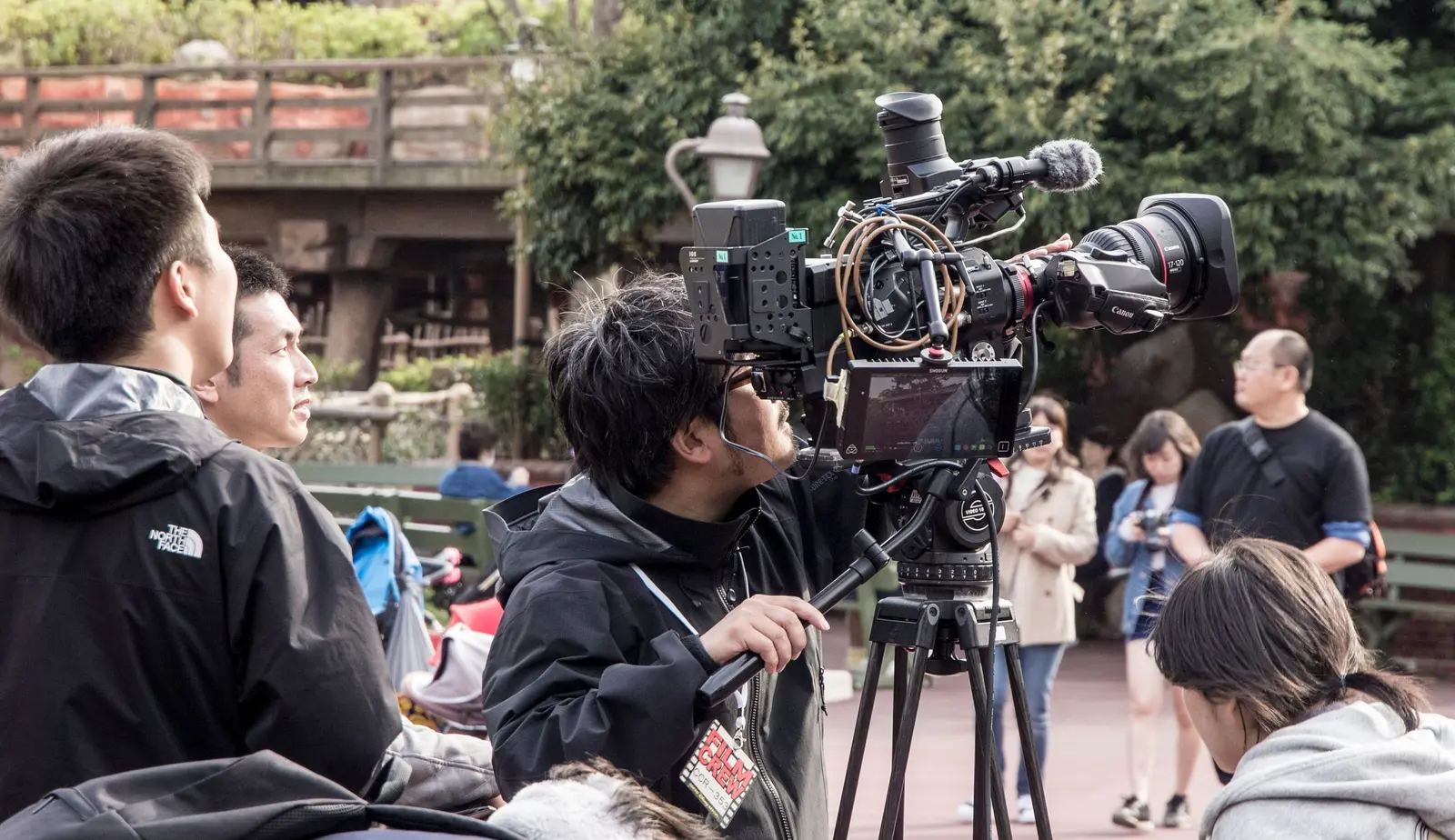 A camera operator and film crew working on location