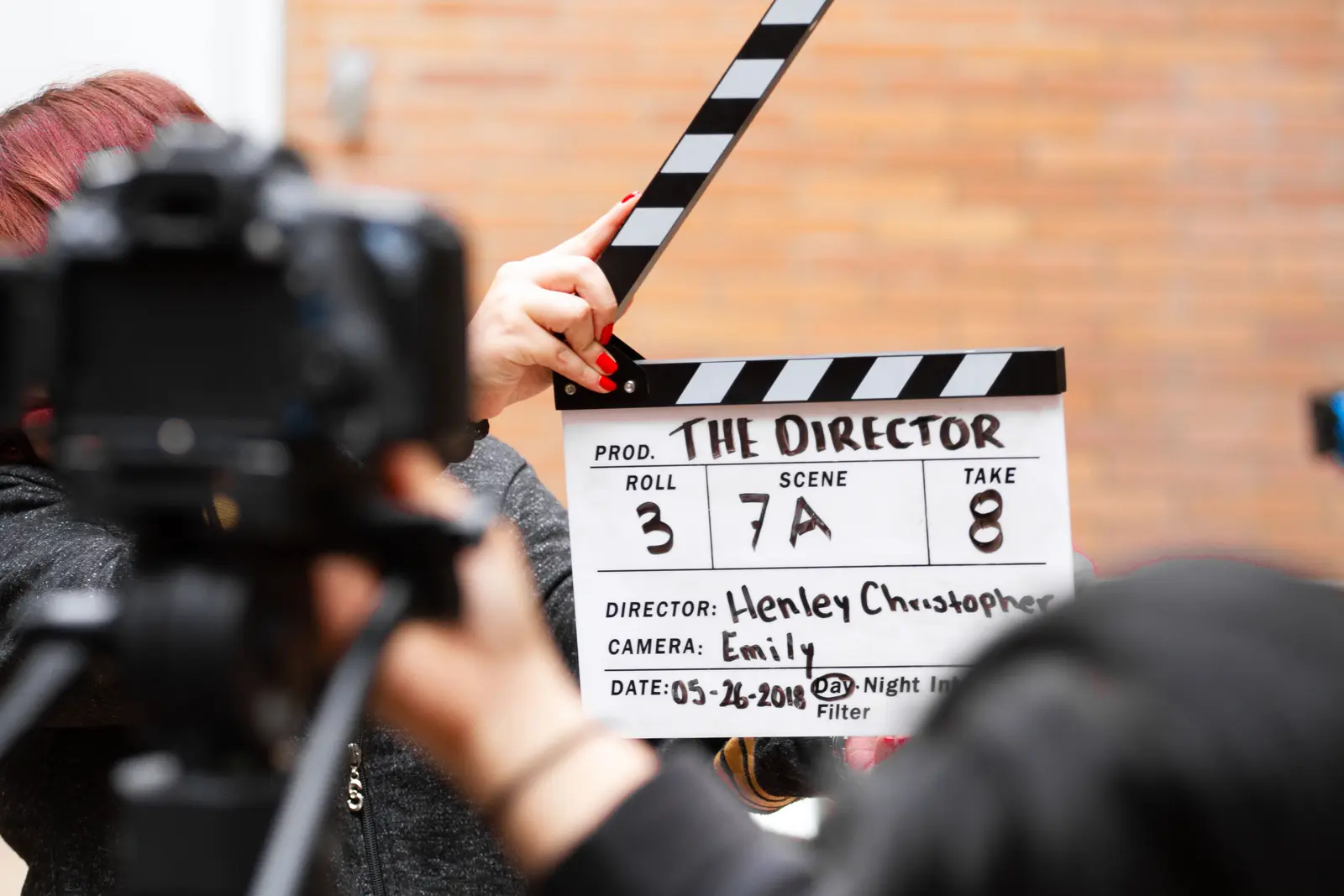 A crew member holding a clapperboard beside a film camera
